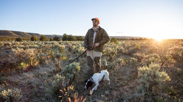 Image of Alex Young in rural setting with long gun and dog.  