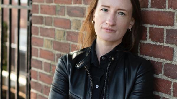 Dr. Ieva Jusionyte headshot, leaning against brick wall